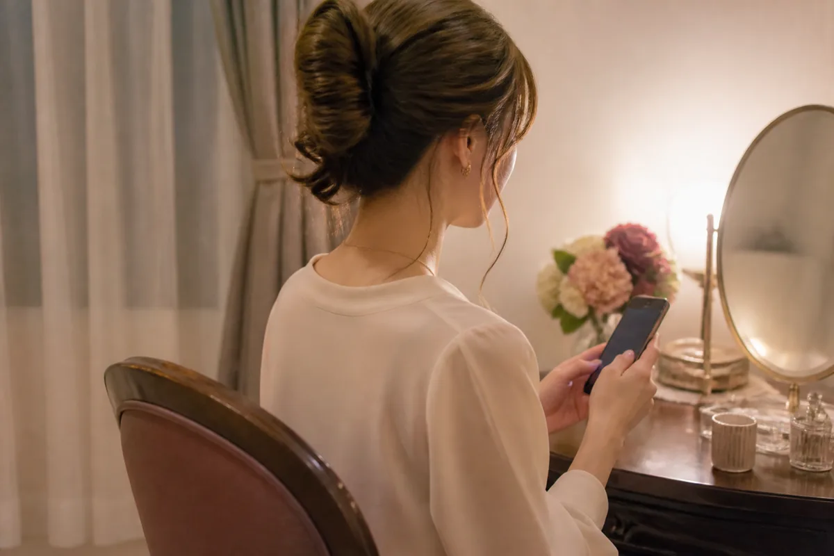 支度部屋でスマートフォンを確認する成人女性のブランドイメージ